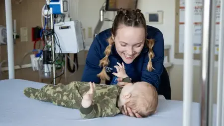 护理 学生 caring for an infant on a examination table.